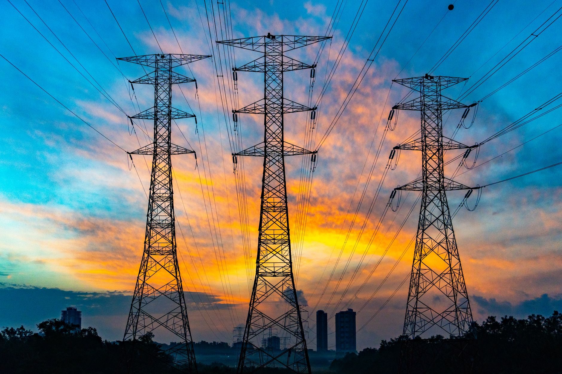 High voltage transmission towers against a sunset sky, the grid constraint every data center now runs into