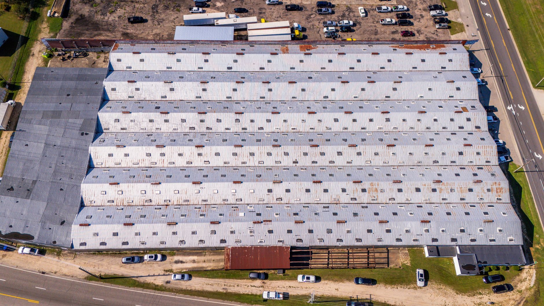 Aerial view of a large flat commercial warehouse roof, the kind of surface a panel field is laid across